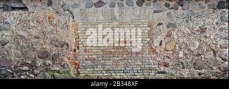Wall of vintage  rural barn shed  for storage of firewood and agricultural tools made of granite stones and clay bricks Stock Photo