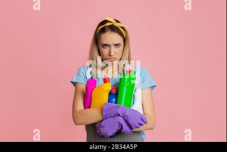 Unhappy woman with bottles of cleanser in hands Stock Photo