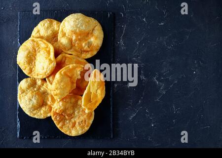 Bhature, indian deep fried leavened bread on a black slate tray on a concrete table, horizontal view from above, flat lay, free space Stock Photo