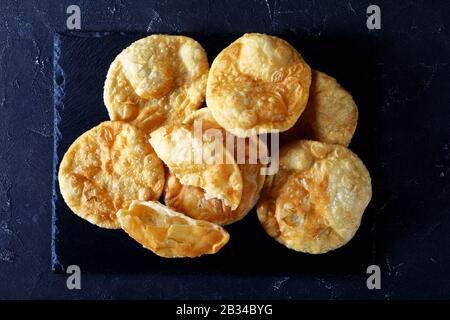Bhatura, indian deep fried leavened bread on a black slate tray on a concrete table, horizontal view from above, flat lay, close-up Stock Photo