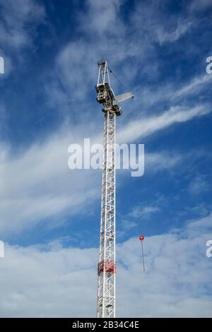 Looking up at a white tower crane against a blue sky with white clouds, central London, UK Stock Photo