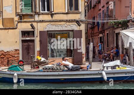 Builder taking a rest on barge, Venice, Italy Stock Photo