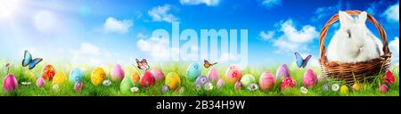 Easter Eggs And Adorable Bunny In Basket On Grass Stock Photo