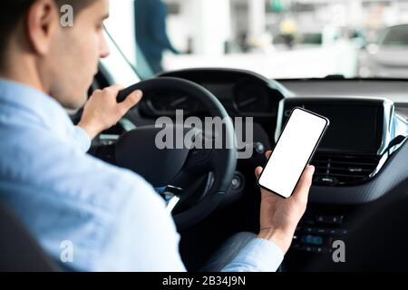 Man Using Smartphone Sitting In Car In Auto Center Stock Photo