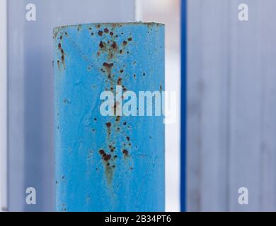 A rusty metal pipe, Rust through the blue paint on an iron post. Stock Photo