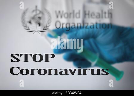 Stop Coronavirus, a blurry World Health Organization logo and the doctor holds an injection in his hand. Stock Photo