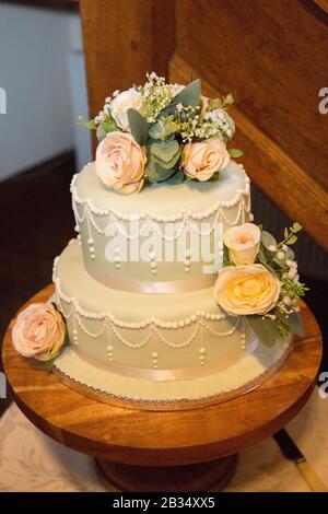 Two tier wedding cake, pistachio green wedding cake with real flowers decorating the top of the cake on a wedding day in England Stock Photo