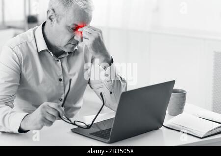 Senior manager massaging nose suffering from pain Stock Photo