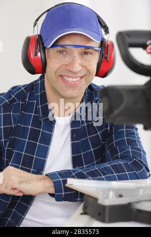 happy workman cutting wooden planks using circular saw in workshop Stock Photo