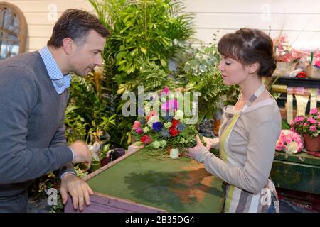 seller helping male client to choose flowers Stock Photo