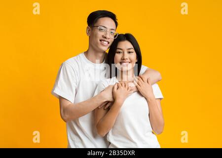 Young asian man and woman hugging on yellow Stock Photo