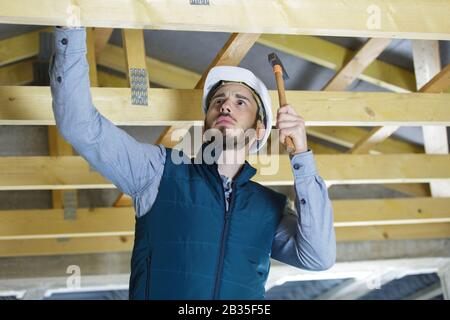 contractor installing wood panels on a ceiling Stock Photo