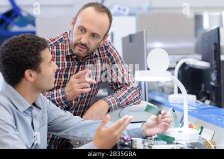 two technician examining a mechanical part in the workshop Stock Photo