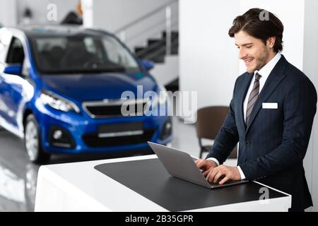 Young Car Seller Standing In Luxury Dealership Office Stock Photo