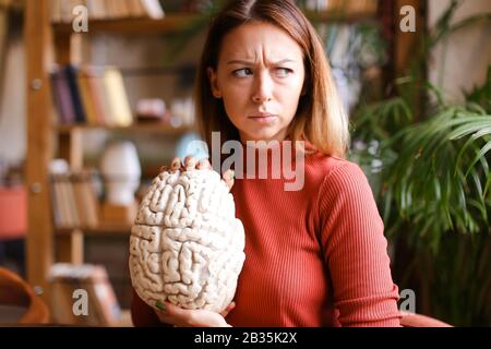 Strict woman holding human brain model in class room. Stock Photo