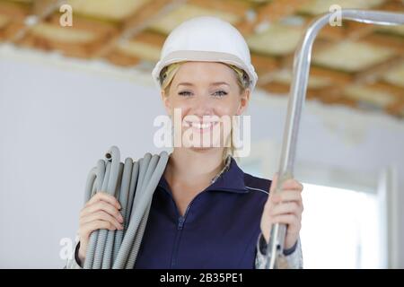 portrait of female builder carrying reel of cable Stock Photo