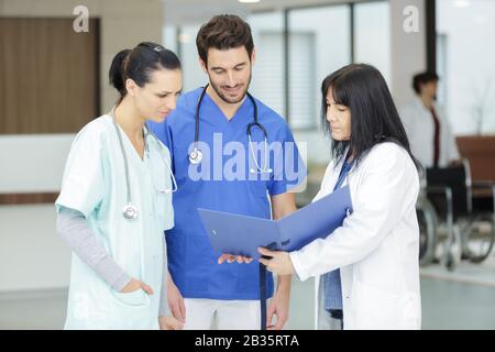 three medical workers looking at folder and conferring Stock Photo