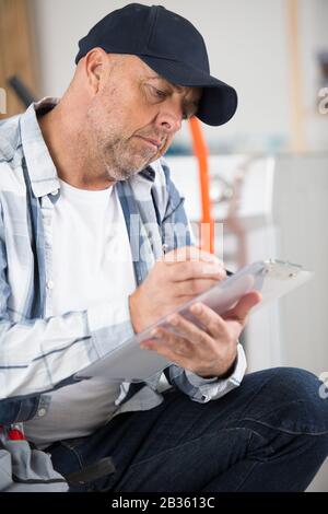 senior tradesman writing on a clipboard Stock Photo