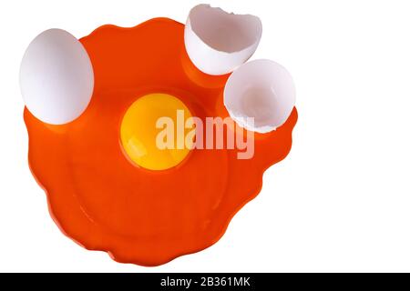 Orange raw egg with yellow yolk on white background isolated close up top view, uncooked broken and whole eggs on red backdrop, art Easter banner Stock Photo
