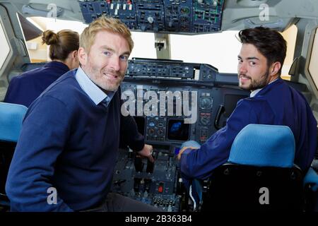 mechanic showing young men inside of cockpit Stock Photo