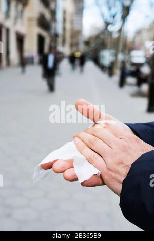 closeup of a caucasian man on the street disinfecting his hands with a wet wipe Stock Photo