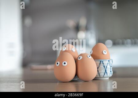 Cheerful easter eggs on the kitchen table, easter egg hunt, egg characters with funny faces, easter concept, kitchen in the background, easter theme, Stock Photo
