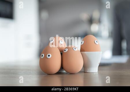 Cheerful easter eggs on the kitchen table, easter egg hunt, egg characters with funny faces, easter concept, kitchen in the background, easter theme, Stock Photo