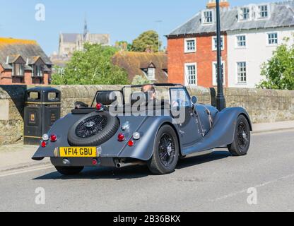 Man driving a 2014 Morgan 4/4 (Morgan Four Four) car, a small convertible sports car with the top down in Summer in England, UK. Stock Photo