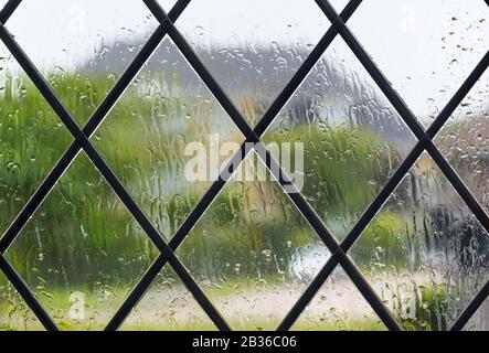 Rain on window when looking outside while raining on a wet day of typical British weather, to illustrate staying home due to COVID19. Stock Photo