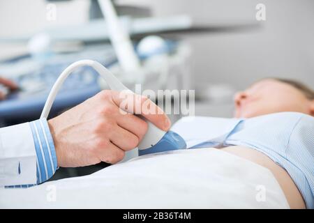 Doctors hand moving transducer on woman belly Stock Photo