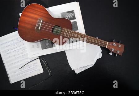 Musical note, glasses and ukulele on a black background Stock Photo