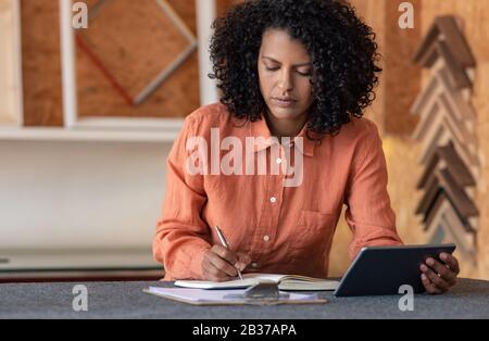 Young woman writing notes while working in her framing shop Stock Photo