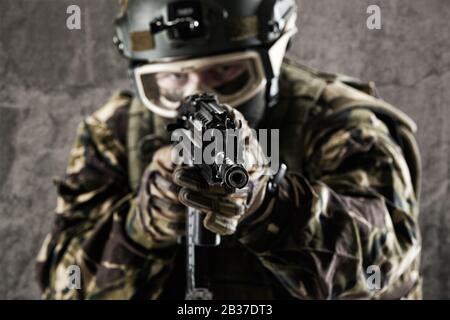 A special forces soldier holds a gun in his hands and looks into the camera. Stock Photo