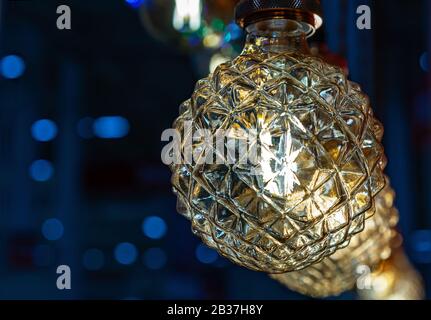 Round light bulb with dark faceted glass on a blue background. Stock Photo