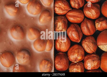 Chocolate with hazelnuts, nuts in a shell in the form of a solid texture. Dessert-milk chocolate with nuts. Confectionery. Full screen top view Stock Photo