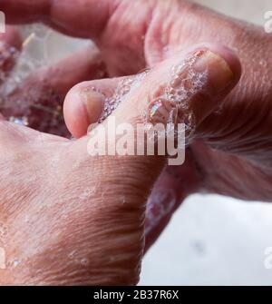 Wash hands, a man washes his hands under the tap with soap and water. A man rinsing his hands under flowing water Stock Photo