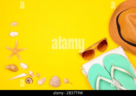 Sea shells and starfish on yellow background. Swim towel, sun glasses, beach shoes and straw hat. Summer mood mockup Stock Photo