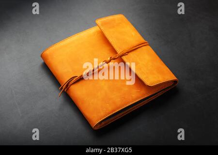 The album cover is made of brown genuine leather, handmade on a black background. Elements of a leather product close-up. Kraft Stock Photo