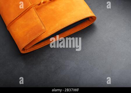 The leather cover of the album is made of brown handmade genuine leather on a black background. Elements of a leather product close-up. Craft, low con Stock Photo