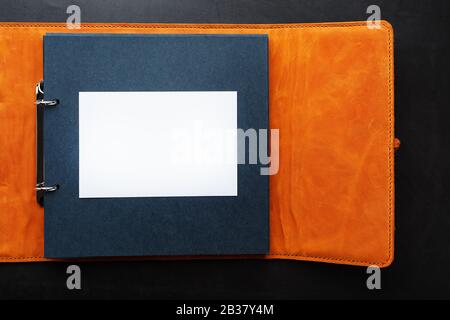 Open photo Album with empty space for photos, white frames on black paper. The album cover is made of brown handmade genuine leather on a black backgr Stock Photo