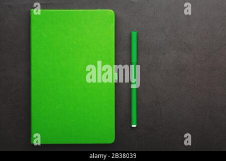 Green Notepad with a felt-tip pen on a black background, top view. Free space. Stock Photo