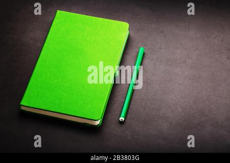 Green Notepad with a felt-tip pen on a black background, top view. Free space. Stock Photo