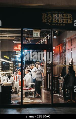 London, UK - December 14, 2019: View through the window of men getting haircuts inside Barber Barber, an award-winning barbershop inside Spitalfields Stock Photo