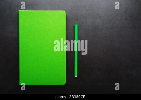 Green Notepad with a felt-tip pen on a black background, top view. Free space. Stock Photo