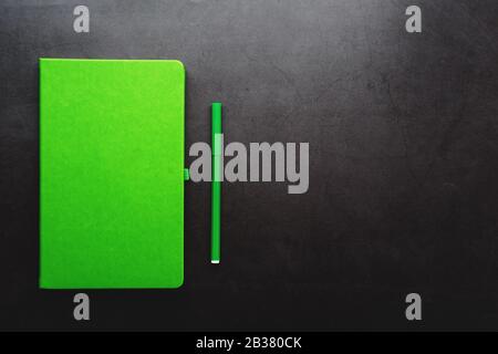 Green Notepad with a felt-tip pen on a black background, top view. Free space. Stock Photo