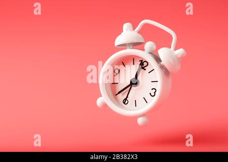 White retro style alarm clock in levitation isolated on pink background. Arrows on the time 7: 00. Minimalistic creative modern still life photography Stock Photo
