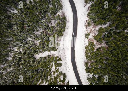 Flight over the winter mountains with road serpentine and snowy forest. Top down view. Landscape photography Stock Photo