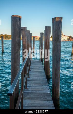 Pier wooden poles tightened together by rusty chains on canal in Venice Stock Photo