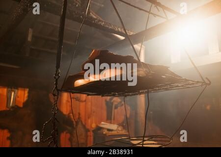 National smokehouse in the house of a mountain village with an open fire on the floor. Smoked cheese of national cuisine Stock Photo