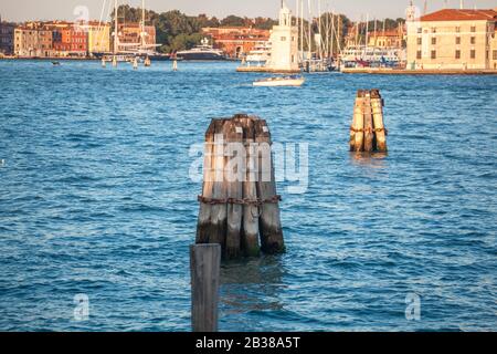 Pier wooden poles tightened together by rusty chains on canal in Venice Stock Photo